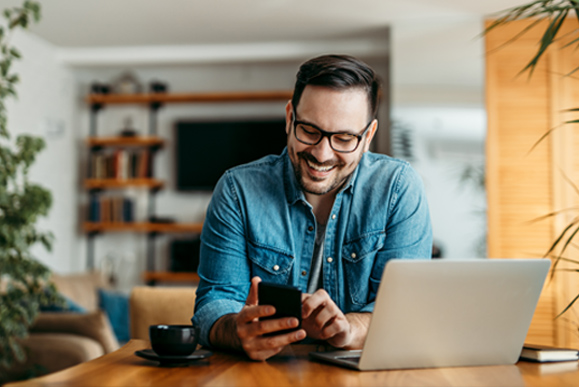 Happy vWise user on laptop with phone in hand